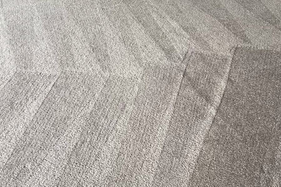 Freshly cleaned living-room carpet with even wand stripes beside a fireplace