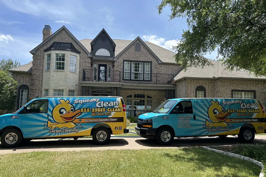 Two Squeaky Clean vans parked outside a large brick home